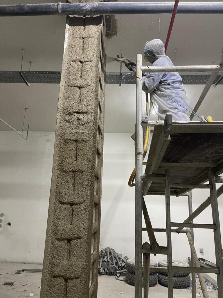 Applying cementitious fireproofing, to protect the steel angles in case of fire.